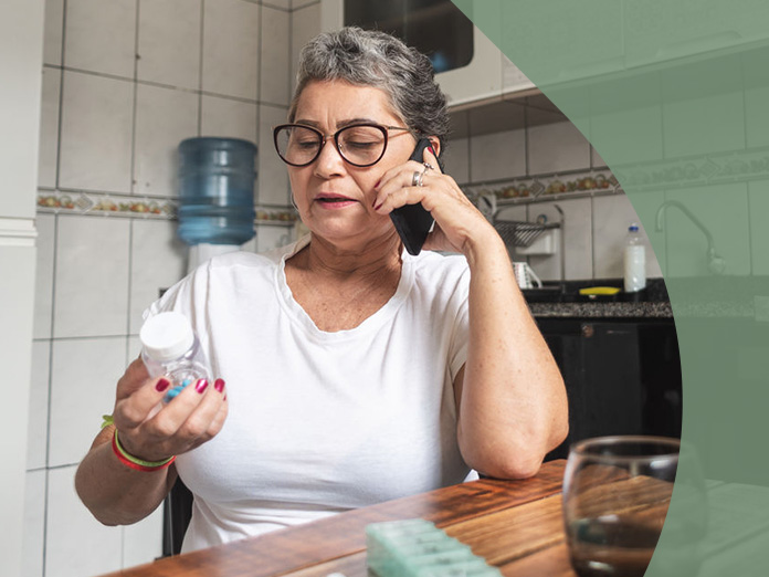 A person holding a pill bottle and calling about a prescription